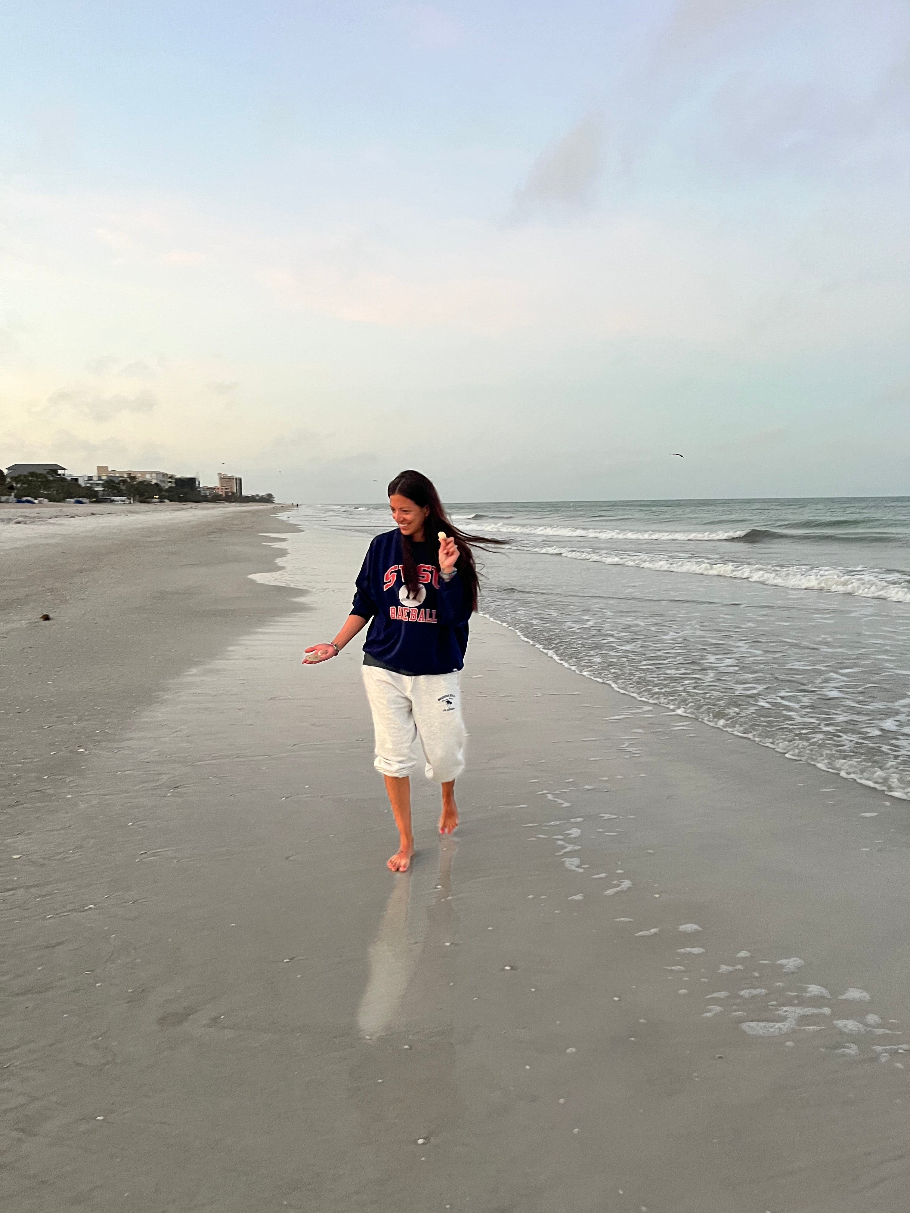 Woman walking on Madeira Beach Florida at sunrise, enjoying the calm Gulf waters and morning light.