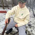 Bone-colored unisex camping hoodie with green All Day Fire Outfitters logo patch. Comfortable outdoor hoodie made for campfire living and adventure.