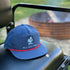 Navy Richardson 256 ropestyle snapback featuring the Columbia Blue All Day Fire Outfitters logo. Outdoor hat available with white or red rope detail.