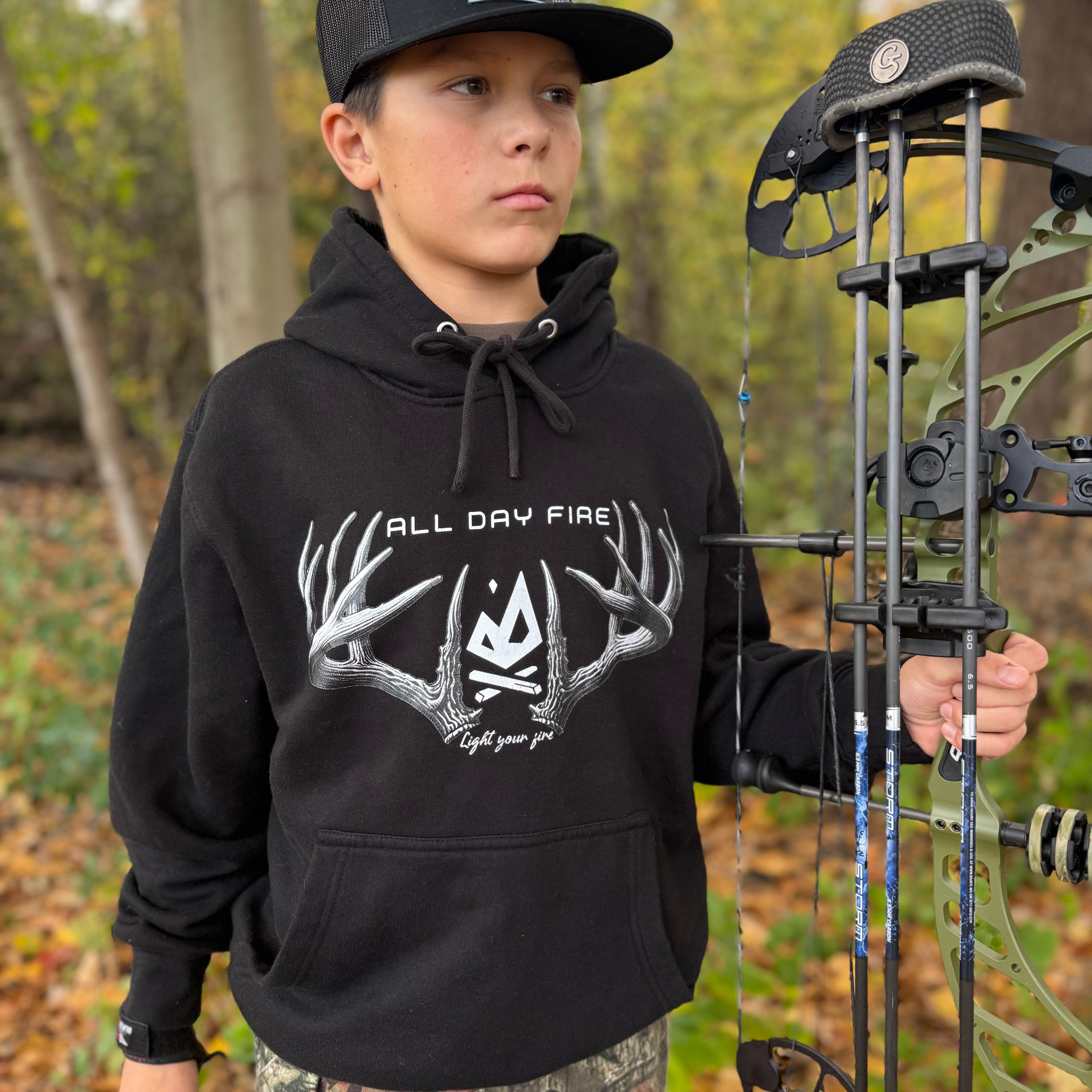 Black hunting hoodie featuring antlered Light Your Fire graphic and All Day Fire Outfitters logo. Midweight cotton poly blend built for outdoor comfort and campfire warmth.