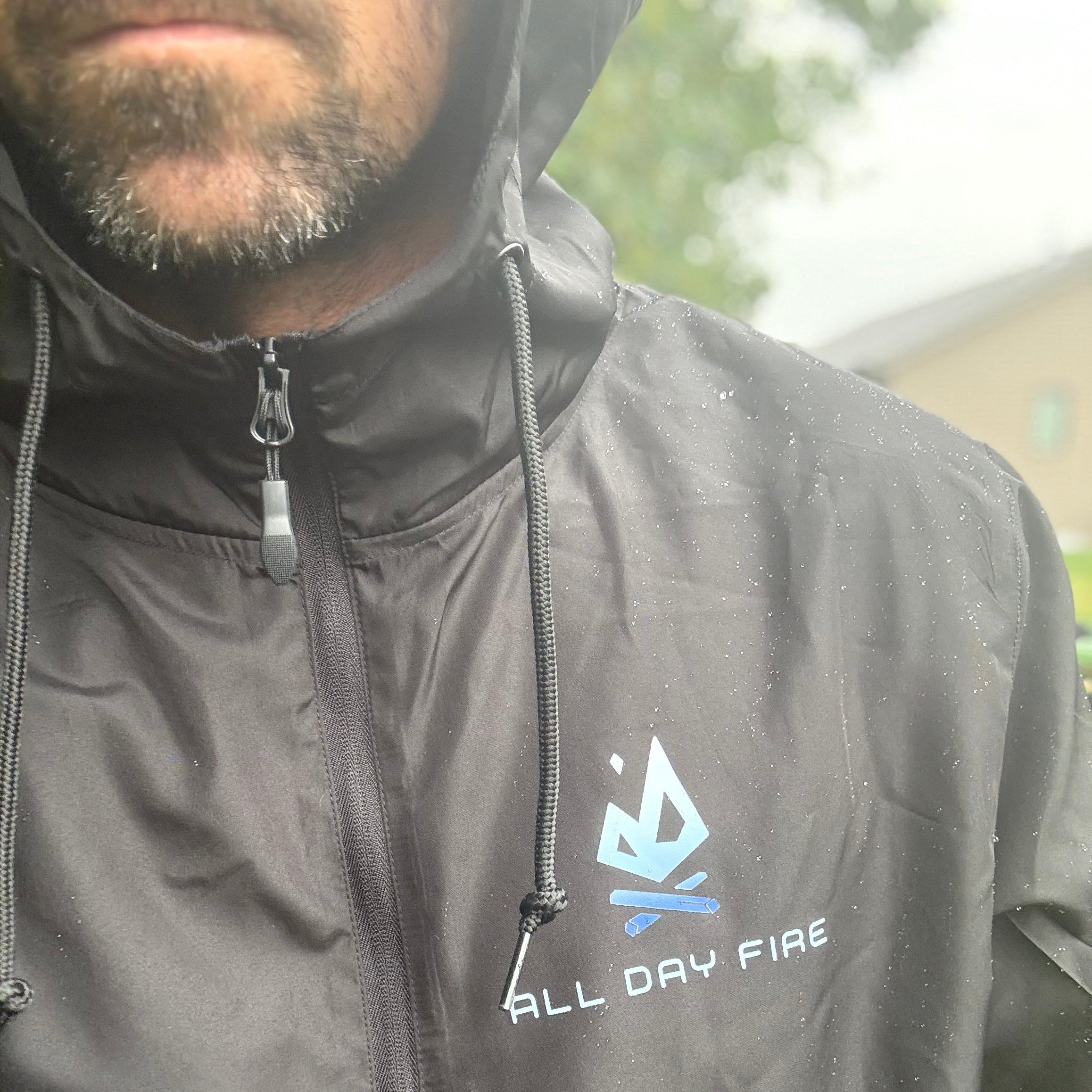 Black 1/4 zip pullover jacket featuring the All Day Fire Outfitters logo patch. Lightweight polyester jacket for rain protection and outdoor comfort.