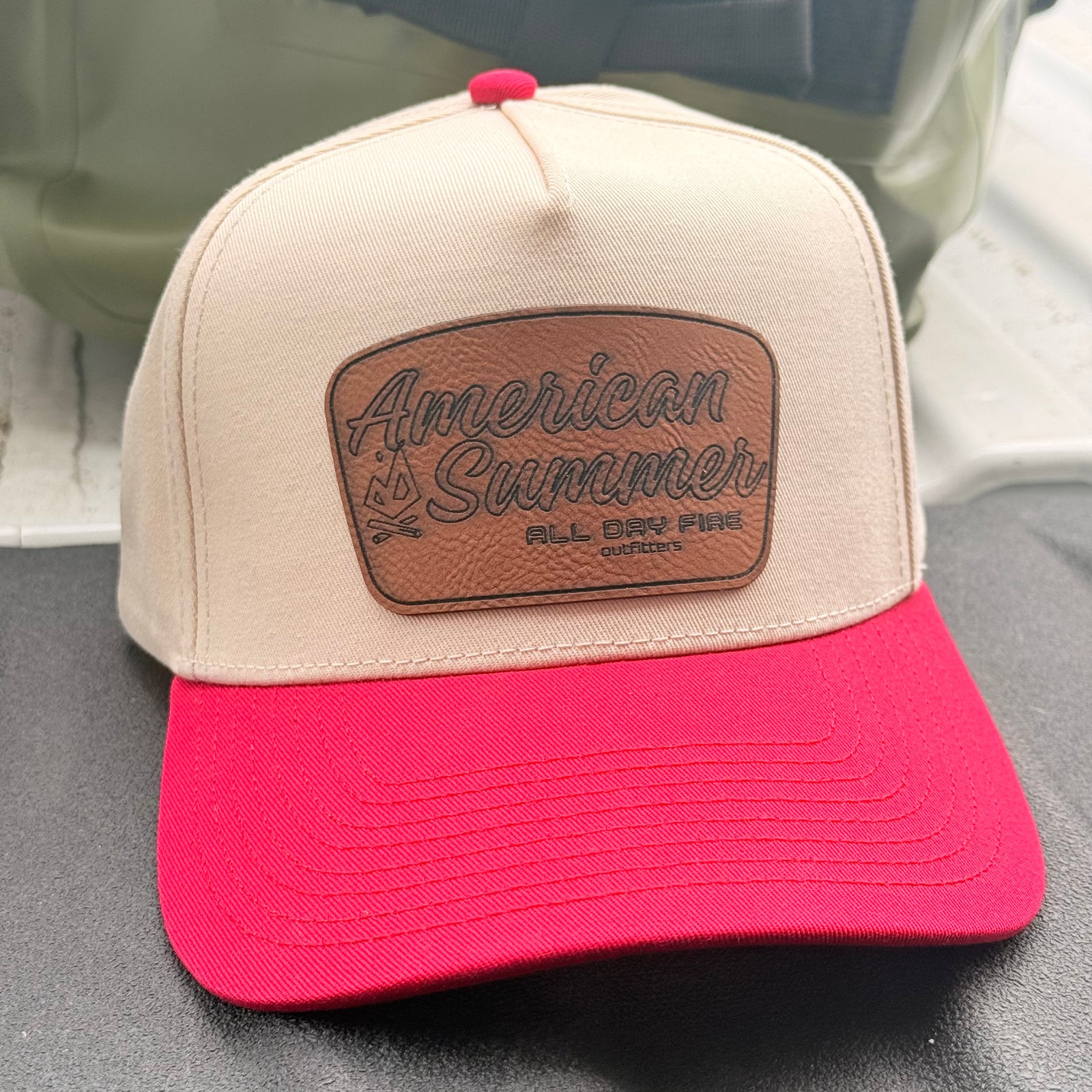 Cream and red American Summer snapback cap featuring a genuine leather patch by All Day Fire Outfitters for camping, campfires, lake days, and patriotic summer adventures.

I actually think this may end up being one of your best-selling hats. The cream and red color combination has a classic Americana feel without looking overly patriotic, so people will wear it well beyond the Fourth of July.