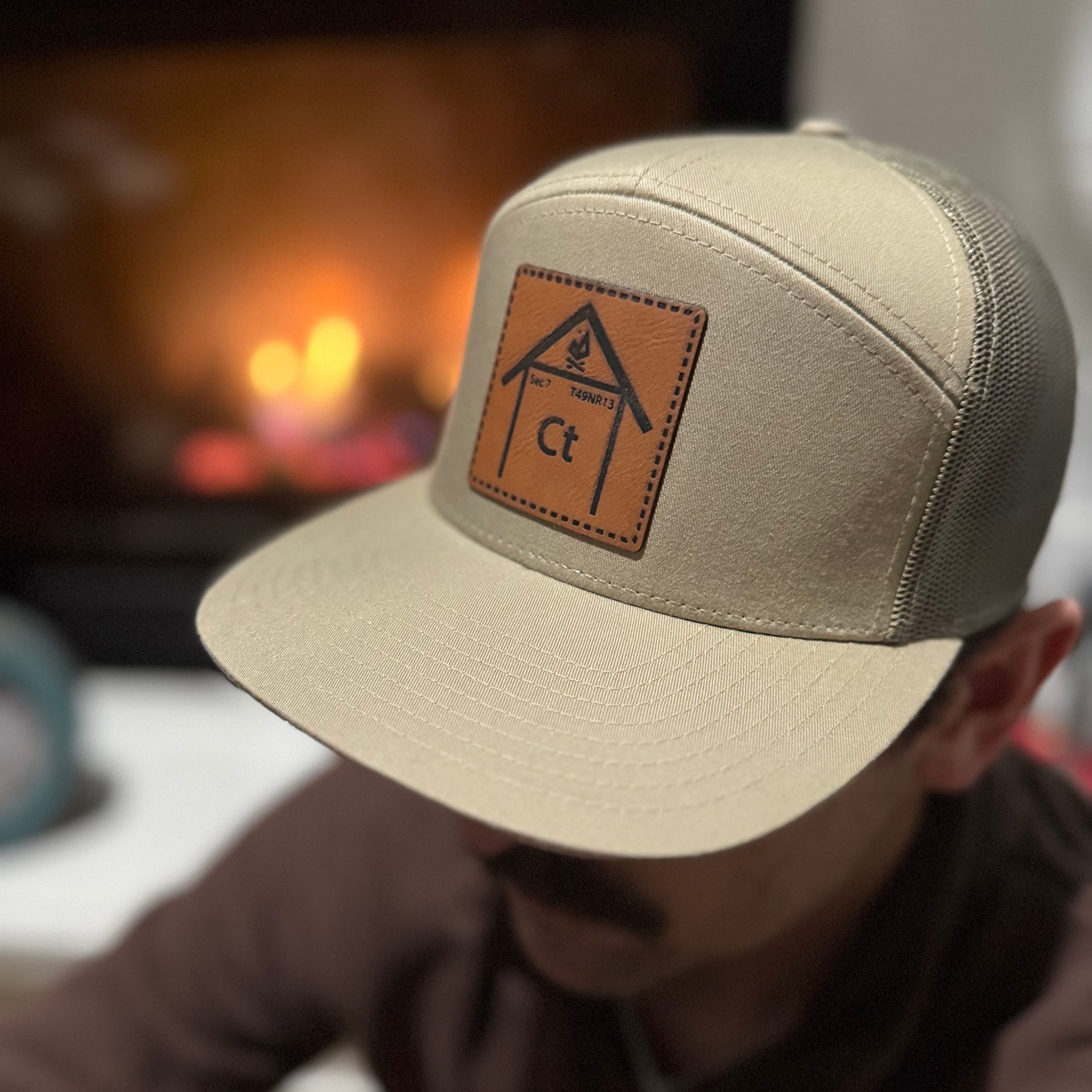 Man wearing Copper Top Edition leather patch hat near a campfire. Richardson 168 7-panel snapback built for outdoor adventures and cabin nights.