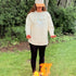Woman wearing the Northbound women's crewneck and embroidered Northbound hat outdoors at a campsite.