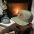 Man wearing Split Early Stay All Day leather patch hat outdoors near a campfire. Richardson 112 5-panel snapback designed for camping and everyday outdoor wear.