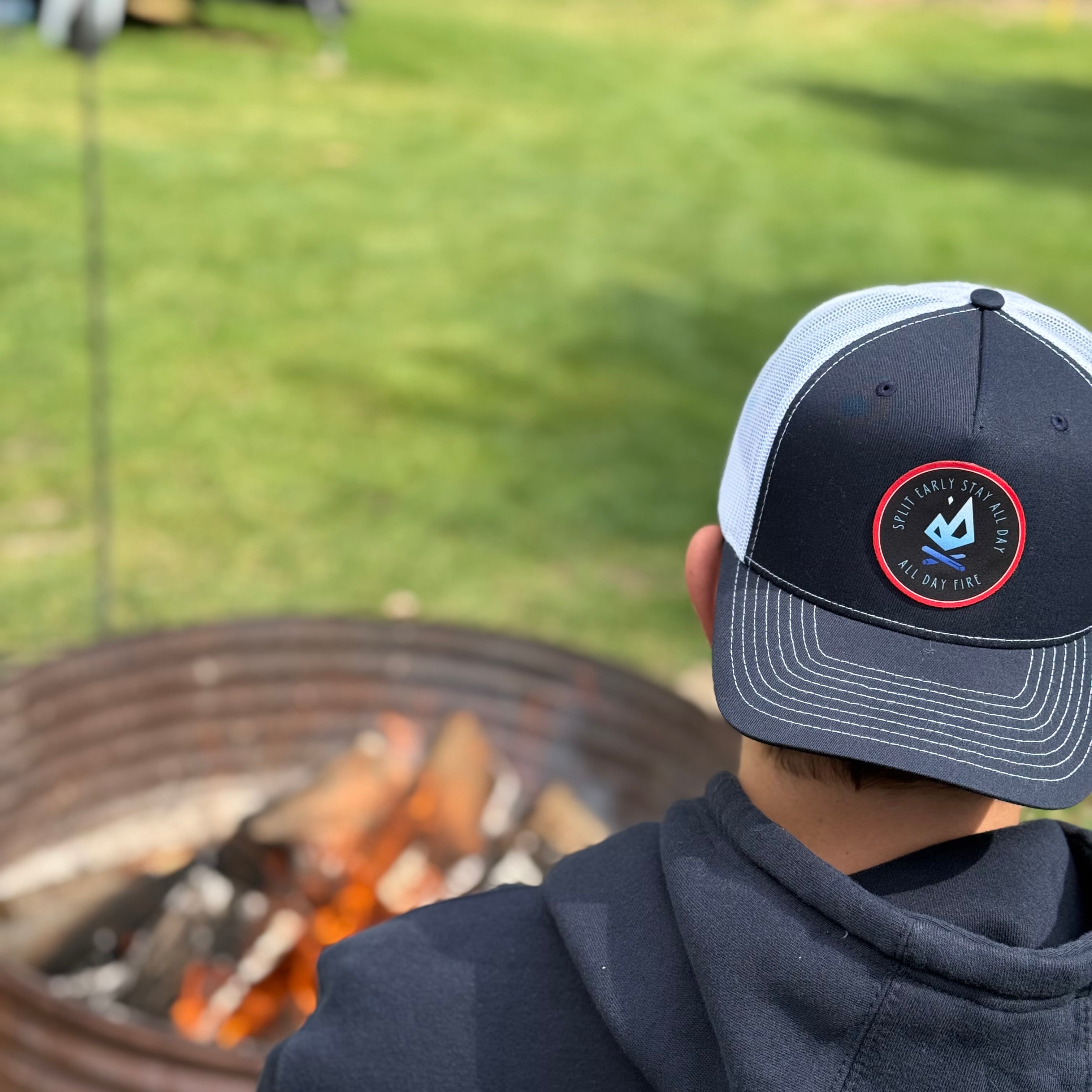 Split Early Stay All Day patch hat resting on a seat near a campfire. Richardson 112 5-panel snapback designed for outdoor living.