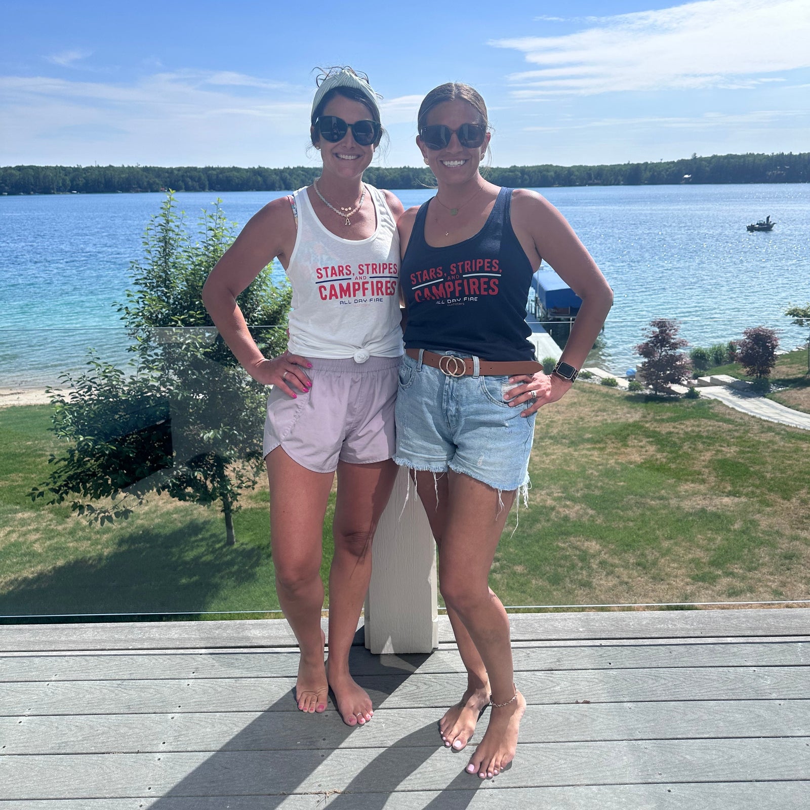 Woman wearing the Stars Stripes and Campfires racerback tank while enjoying a summer campfire at the campground.